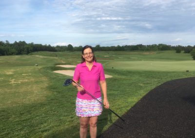 Helene Downs smiling with her golf club at a golf course.