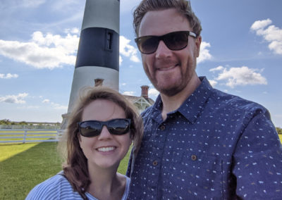 Clarissa Brown Hoffman and her husband smiling in front of a lighthouse.