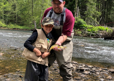 Matthew Hale and his son smiling together with a fish they've caught