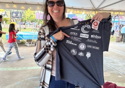 Rebecca Burtram holding up a tshirt from the C3 Party for the Planet event